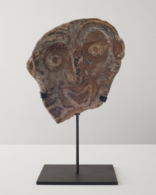 Carved relief stone face on stand